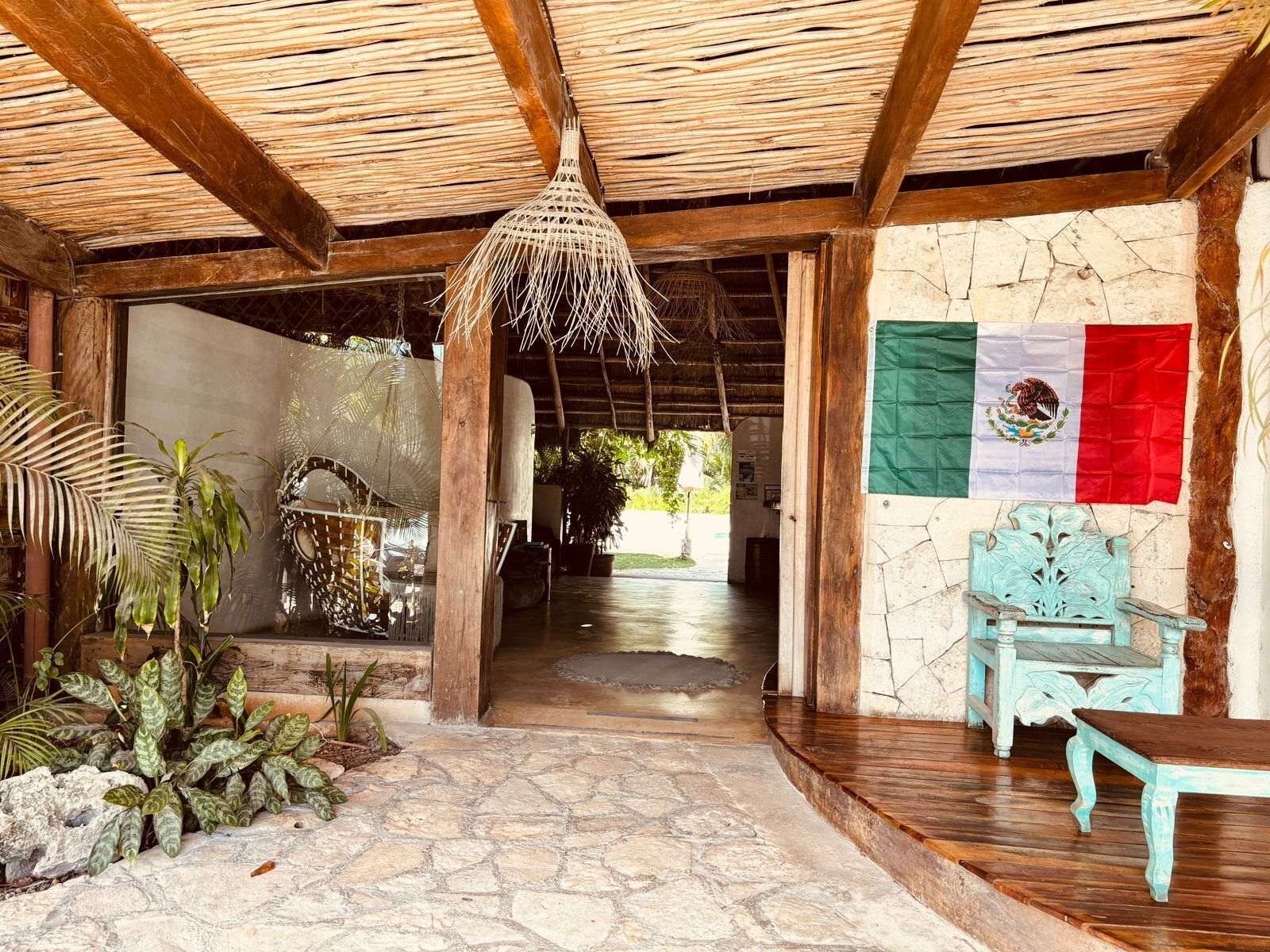Hotel El Capitán Tulum: covered entrance with stone floor, wooden beams and a woven lamp